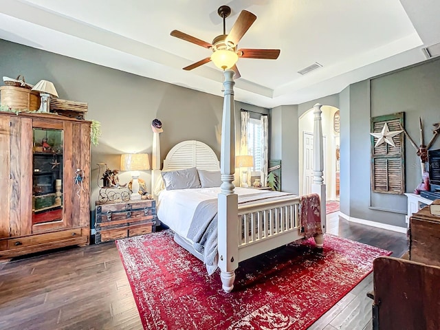 bedroom with a tray ceiling, ceiling fan, and dark hardwood / wood-style flooring