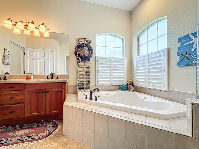 bathroom featuring tile patterned flooring, vanity, and a relaxing tiled tub