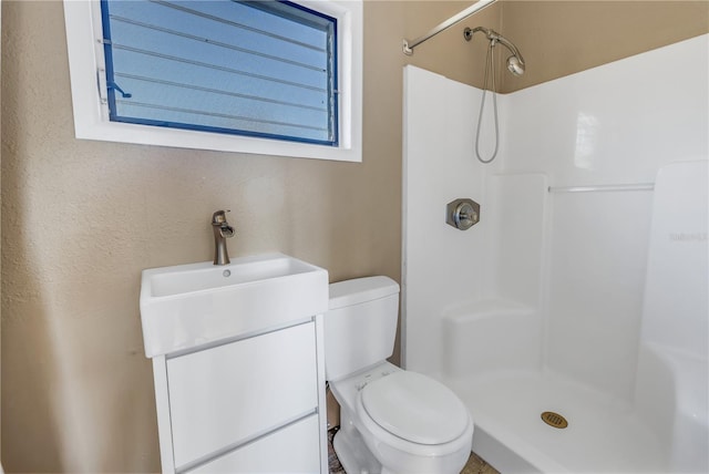 bathroom featuring toilet, vanity, and walk in shower