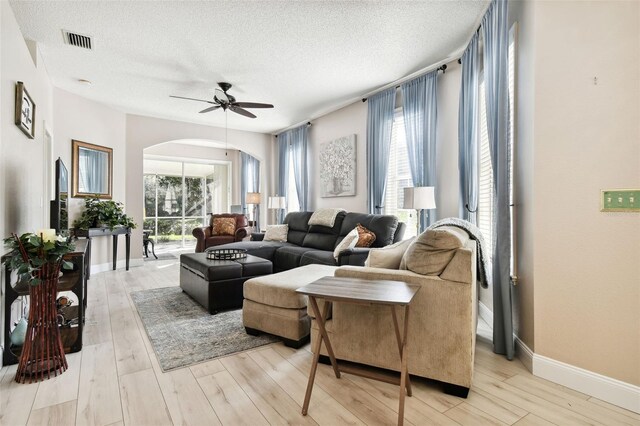 1687 Starling Dr, Tarpon Springs, FL 34689 - living area featuring arched walkways, ceiling fan, a textured ceiling, light wood-style flooring, and baseboards