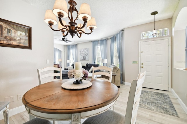 1687 Starling Dr, Tarpon Springs, FL 34689 - dining room featuring a chandelier, light wood finished floors, a textured ceiling, and baseboards