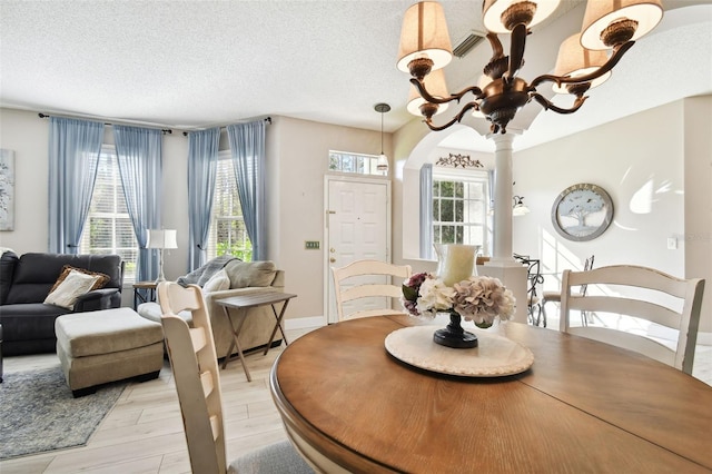 1687 Starling Dr, Tarpon Springs, FL 34689 - dining space featuring light wood-type flooring, a textured ceiling, arched walkways, and baseboards
