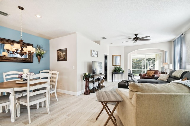 living room with a textured ceiling, light hardwood / wood-style flooring, and ceiling fan with notable chandelier