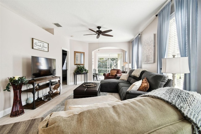 living room featuring a textured ceiling, light wood-type flooring, and ceiling fan