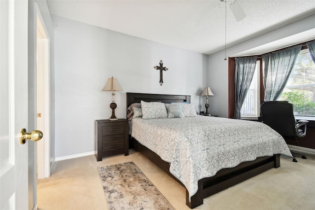 carpeted bedroom featuring ceiling fan and a textured ceiling