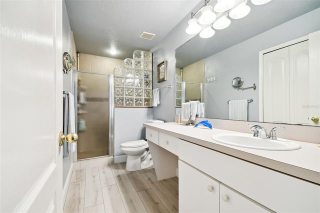 bathroom with wood-type flooring, vanity, toilet, and a shower with door