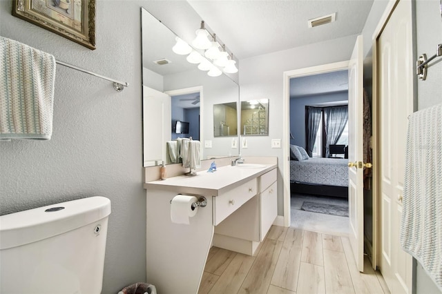 bathroom featuring vanity, toilet, wood-type flooring, and a textured ceiling