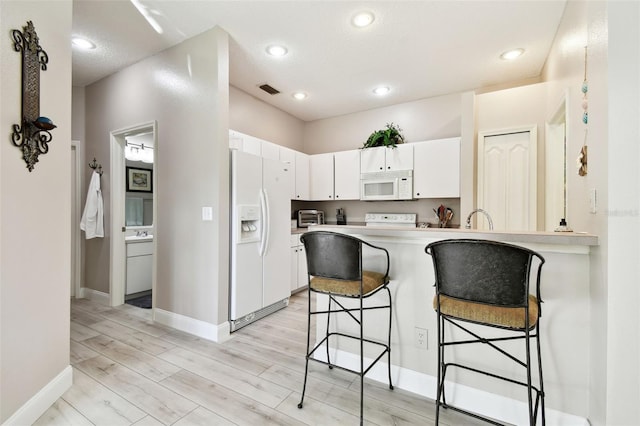 kitchen with white cabinets, light wood-type flooring, white appliances, and kitchen peninsula