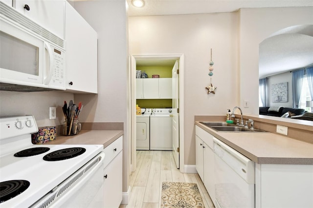 1687 Starling Dr, Tarpon Springs, FL 34689 - kitchen with white appliances, a sink, washer and clothes dryer, white cabinetry, and light countertops