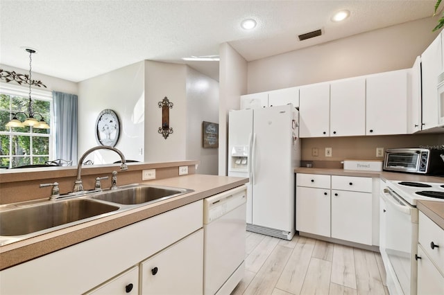 kitchen with white cabinets, pendant lighting, and white appliances