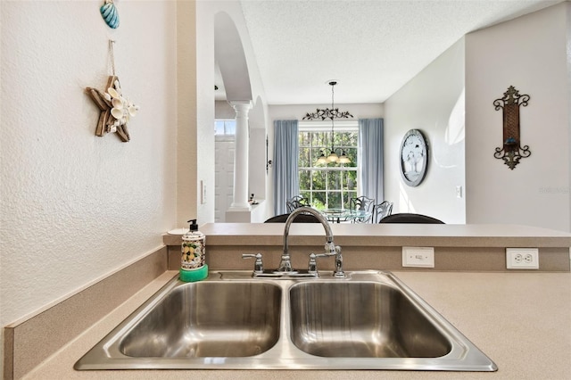1687 Starling Dr, Tarpon Springs, FL 34689 - kitchen with a sink, decorative columns, a textured wall, a textured ceiling, and arched walkways