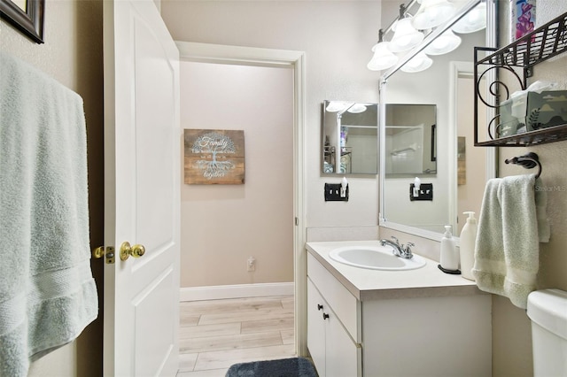 1687 Starling Dr, Tarpon Springs, FL 34689 - bathroom featuring vanity, toilet, baseboards, and wood finished floors