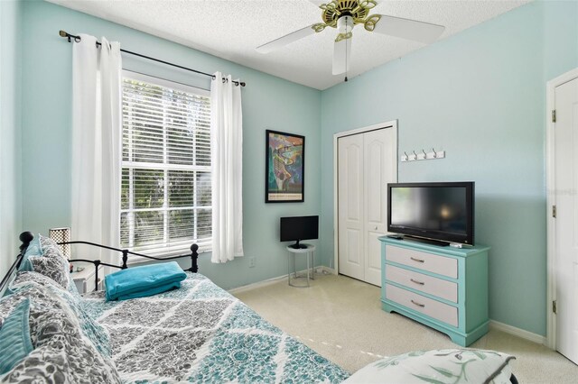 carpeted bedroom with ceiling fan, a textured ceiling, and a closet