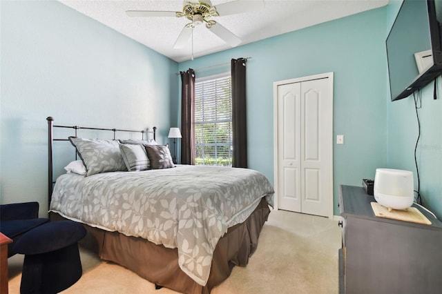 carpeted bedroom featuring ceiling fan, a textured ceiling, and a closet