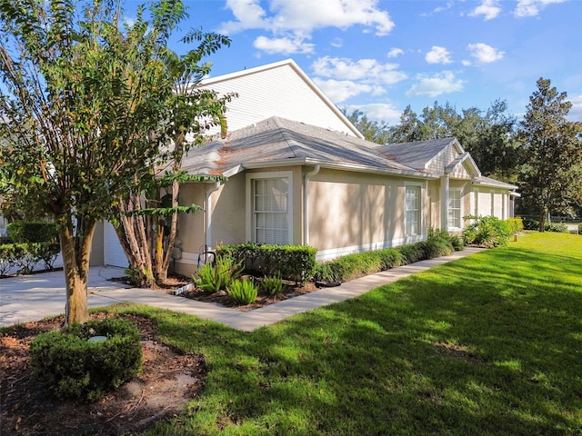 1687 Starling Dr, Tarpon Springs, FL 34689 - view of side of home featuring stucco siding, a lawn, concrete driveway, and a garage