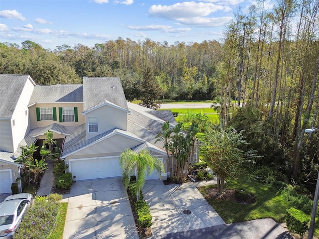 1687 Starling Dr, Tarpon Springs, FL 34689 - view of front facade featuring concrete driveway, a view of trees, a garage, and a shingled roof