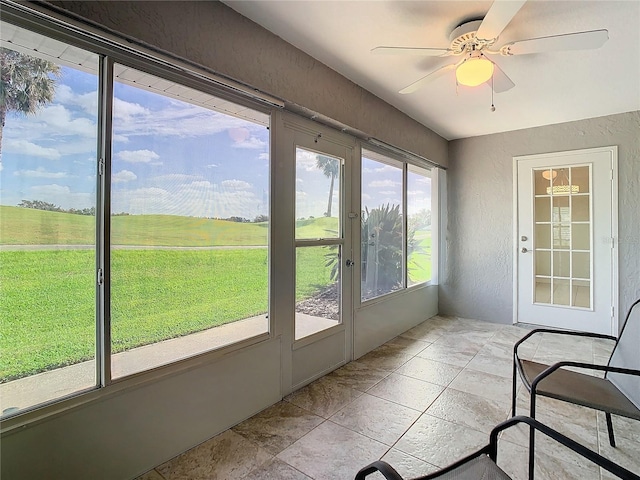 unfurnished sunroom with ceiling fan and a rural view