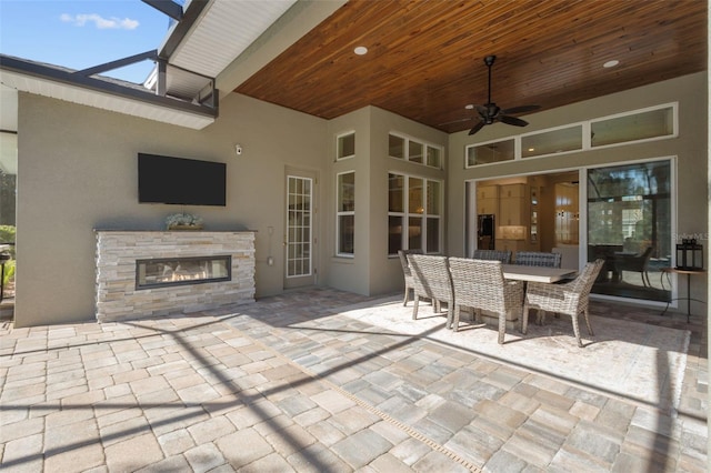 view of patio / terrace featuring ceiling fan and an outdoor stone fireplace