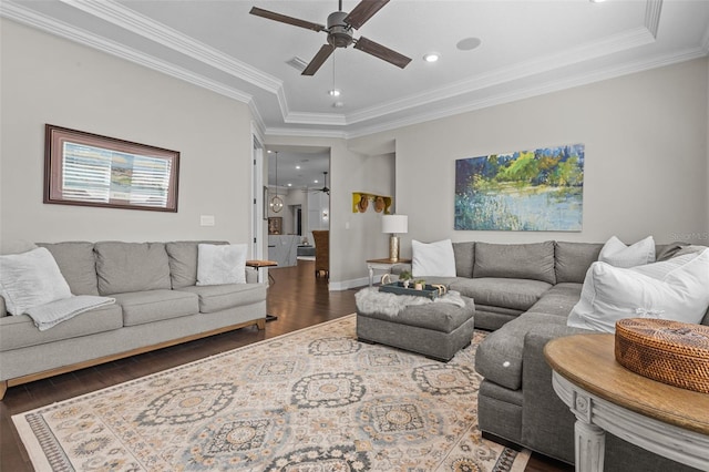 living room featuring a tray ceiling, ceiling fan, dark hardwood / wood-style flooring, and ornamental molding