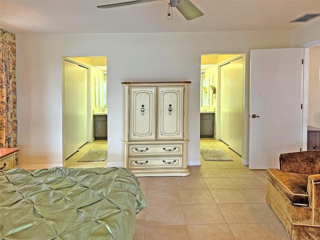 tiled bedroom featuring ensuite bath, ceiling fan, and a textured ceiling