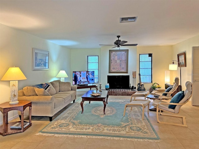 living room with ceiling fan, light tile patterned floors, and a brick fireplace