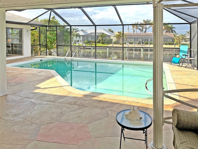 view of swimming pool with a patio, a water view, and glass enclosure