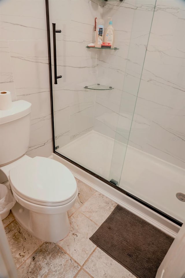 bathroom featuring toilet and a shower with door