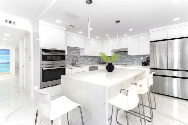 kitchen featuring pendant lighting, a kitchen island, white cabinets, and appliances with stainless steel finishes