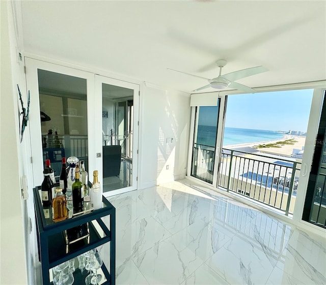 interior space featuring ceiling fan, a water view, and a beach view