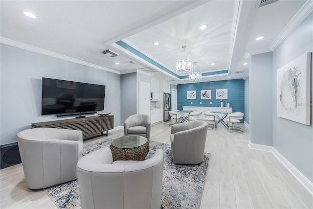 living room featuring a chandelier, crown molding, and a tray ceiling