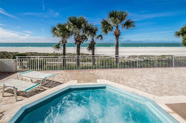 view of swimming pool with a water view, a patio, and a view of the beach