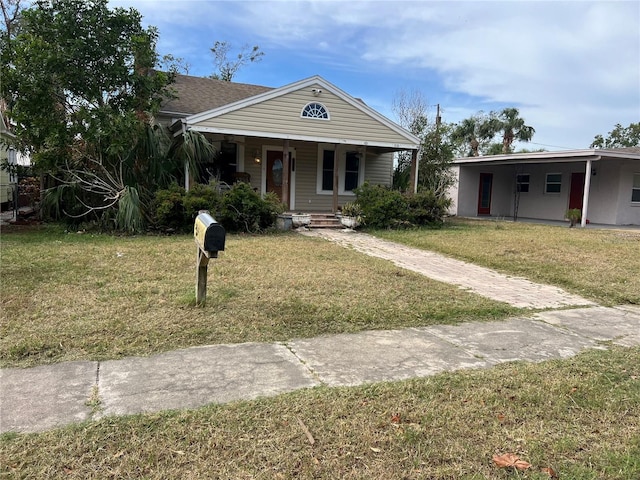 bungalow-style house featuring a carport, covered porch, and a front yard