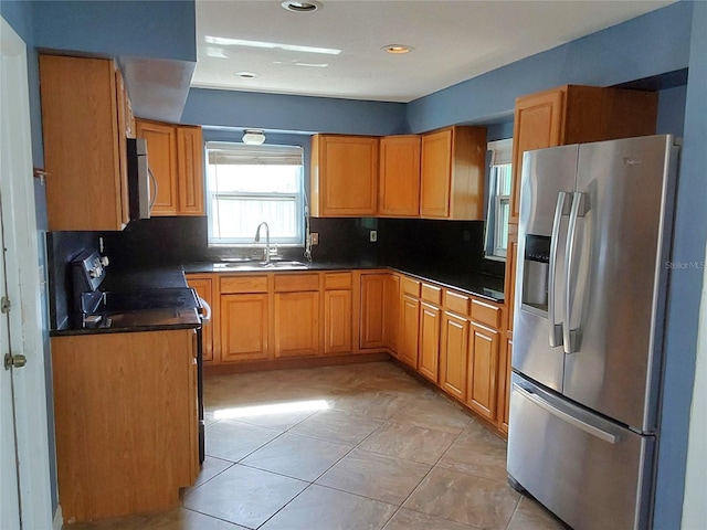 kitchen with backsplash, sink, light tile patterned flooring, and appliances with stainless steel finishes