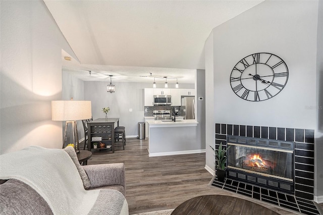 living room featuring a tile fireplace, dark wood-style flooring, a textured ceiling, and baseboards