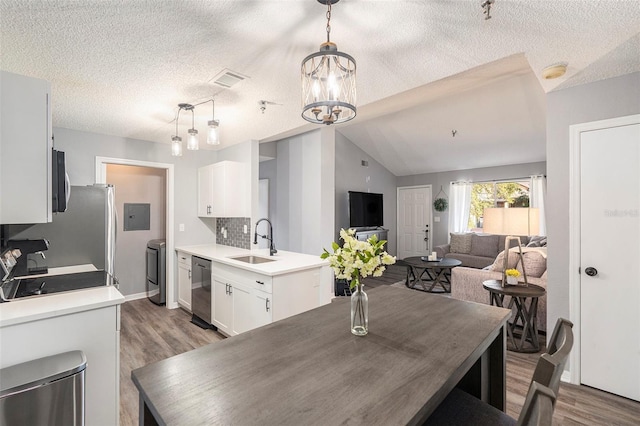 kitchen featuring open floor plan, hanging light fixtures, a sink, and white cabinetry