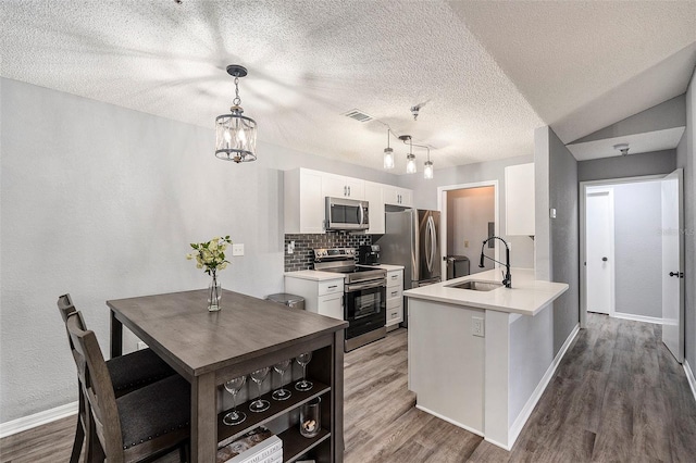 kitchen featuring stainless steel appliances, light countertops, a sink, and white cabinetry