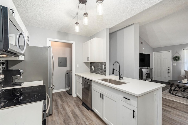 kitchen with decorative light fixtures, stainless steel appliances, light countertops, white cabinetry, and a sink