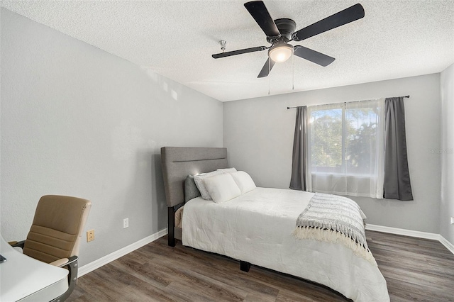 bedroom with a textured ceiling, ceiling fan, dark wood finished floors, and baseboards