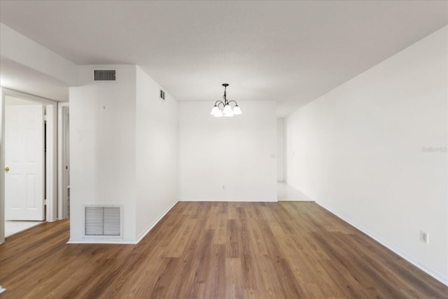 unfurnished room with dark wood-type flooring and a notable chandelier