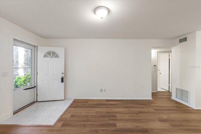 foyer entrance featuring a textured ceiling and light wood-type flooring