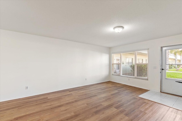 unfurnished room featuring a textured ceiling and light wood-type flooring