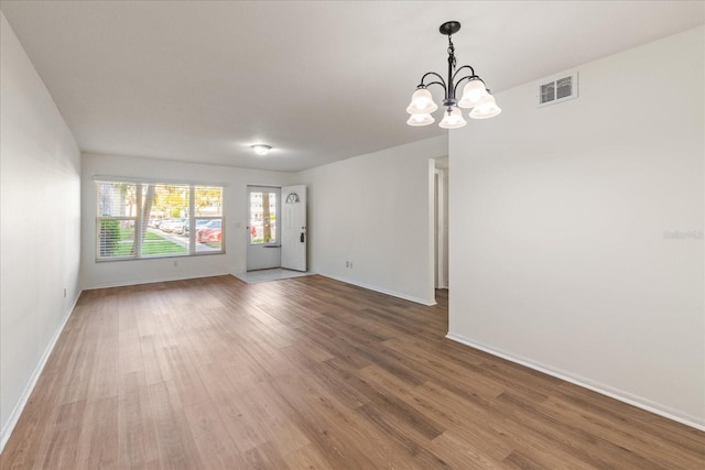 unfurnished room featuring wood-type flooring and a chandelier