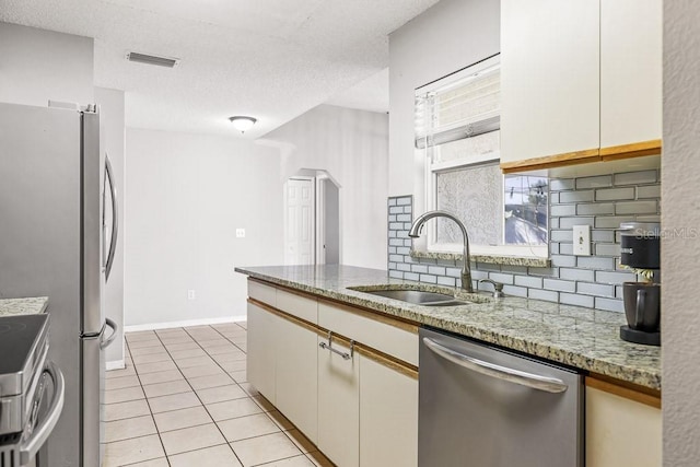 kitchen featuring light stone countertops, tasteful backsplash, stainless steel appliances, sink, and white cabinets