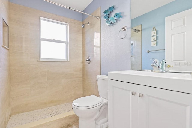 bathroom featuring a tile shower, vanity, and toilet