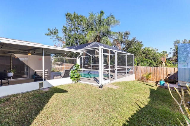 view of yard with glass enclosure, a patio area, a fenced in pool, and ceiling fan