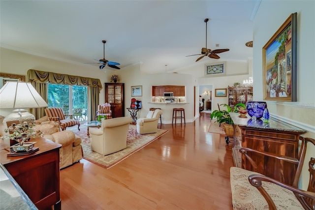 living room with lofted ceiling, ceiling fan, and light hardwood / wood-style floors