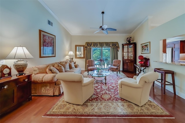 living room featuring vaulted ceiling, hardwood / wood-style flooring, ceiling fan, and crown molding