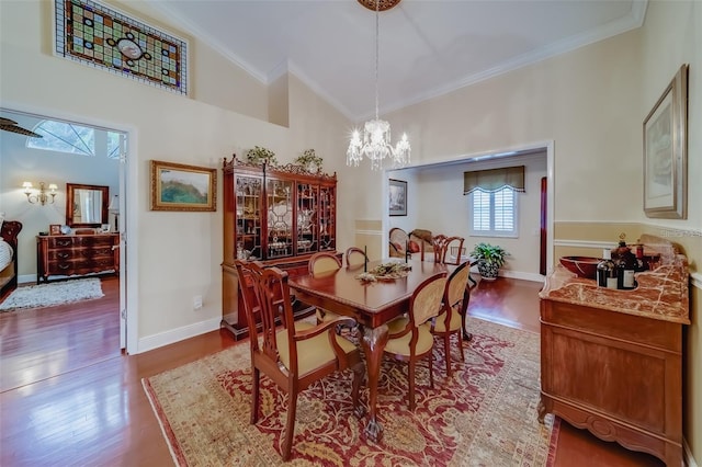 dining area with ornamental molding, a notable chandelier, high vaulted ceiling, and hardwood / wood-style flooring