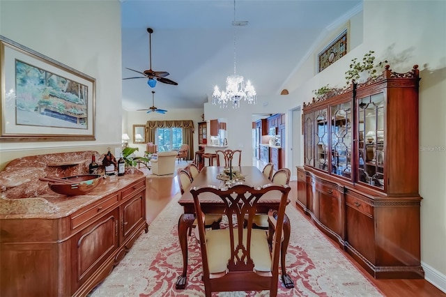 dining area featuring high vaulted ceiling, an inviting chandelier, and light hardwood / wood-style flooring