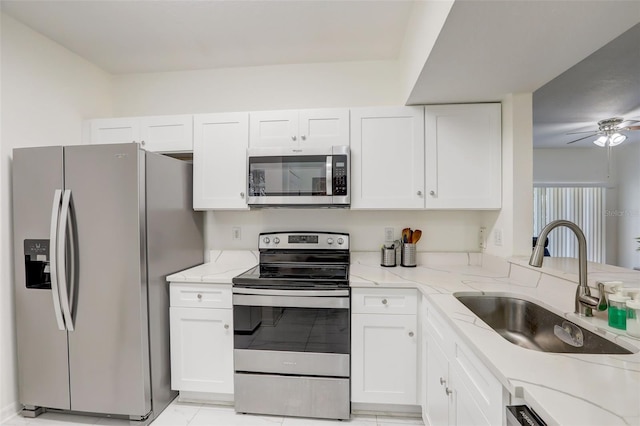 kitchen with light stone countertops, white cabinetry, sink, ceiling fan, and stainless steel appliances